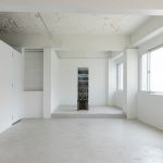Wide view of Fish I–V arranged vertically in a white gallery, with a wooden sculptural object in the foreground.