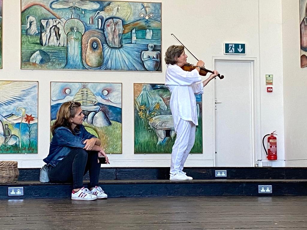 Violinist performing in front of large paintings