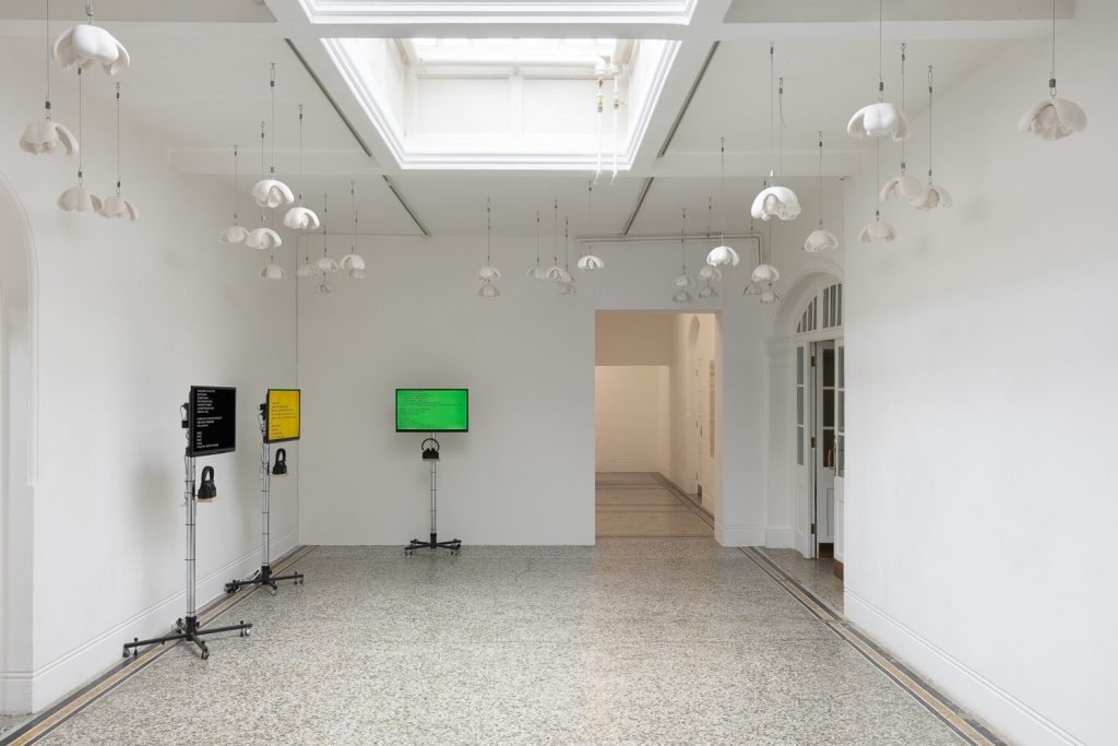 Screens on stands in a skylit gallery