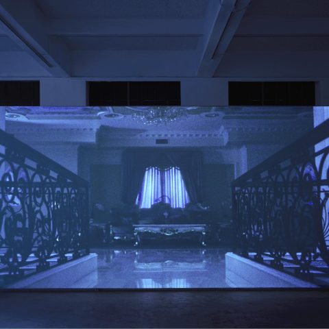 Projection in a darkened gallery with ornate railings