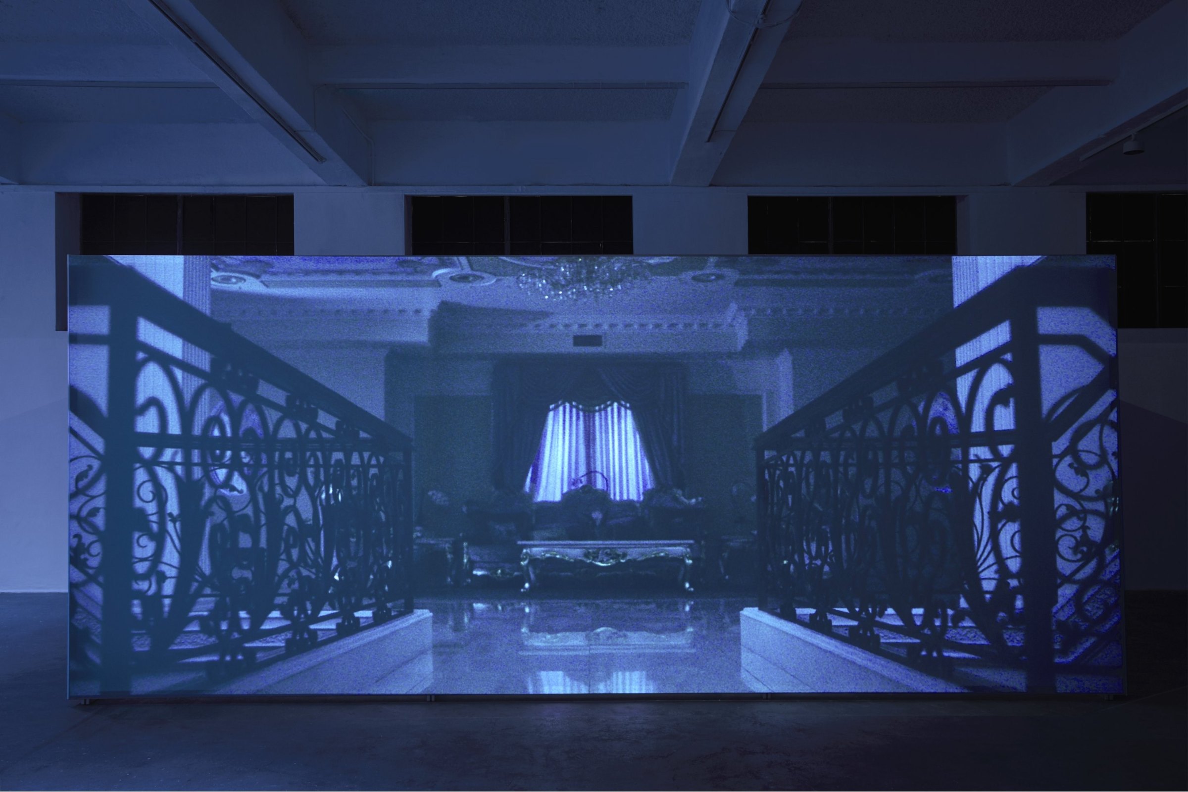 Projection in a darkened gallery with ornate railings