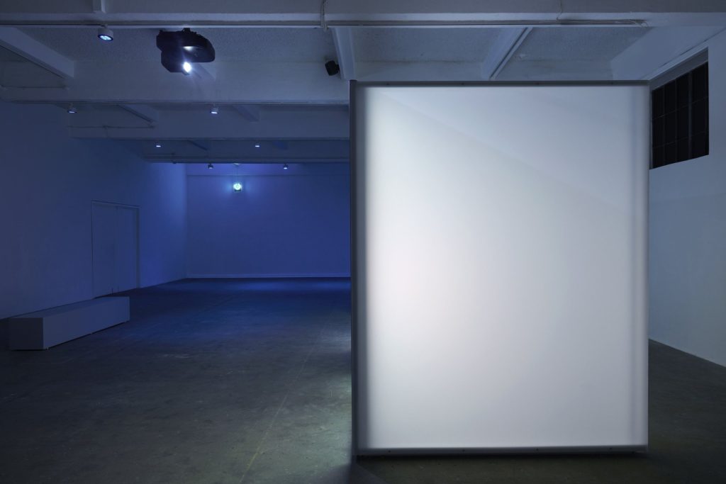 White wall structure lit in a blue gallery