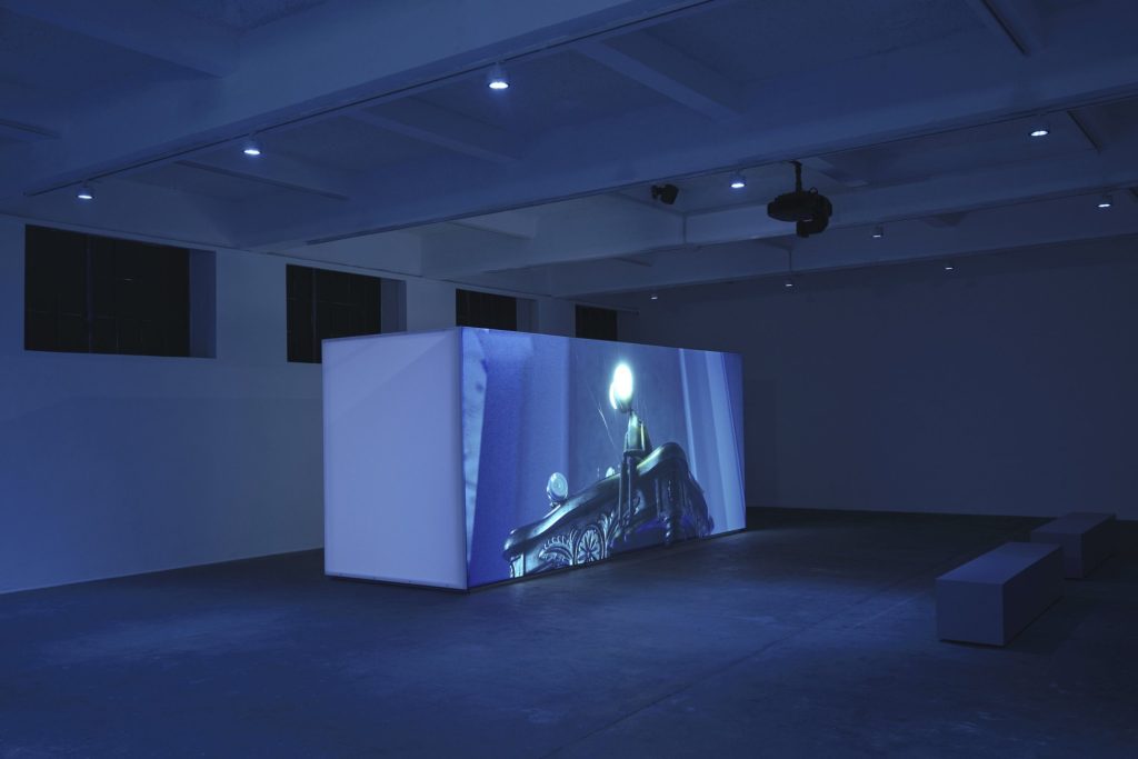 Projection on a freestanding wall in a dark gallery