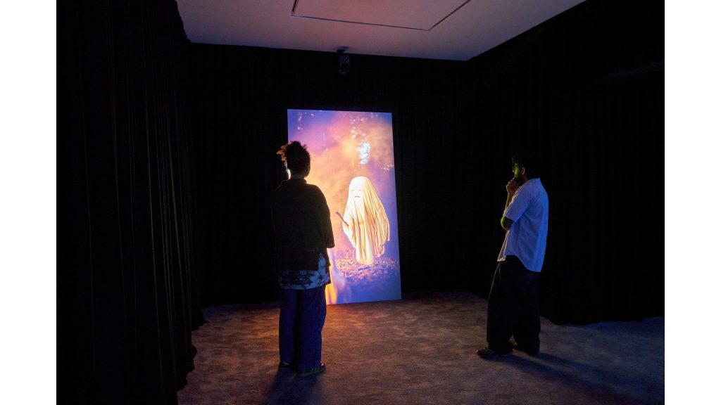 Visitors in front of a tall video screen