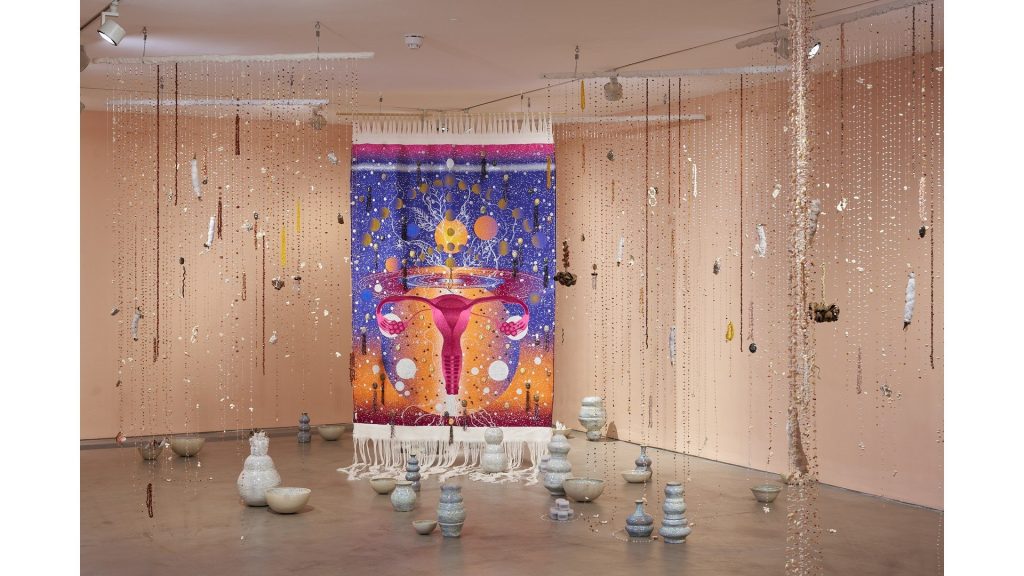 Hanging strands and a textile work in a pink room