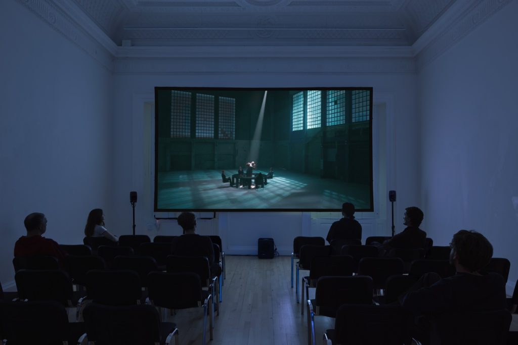 Audience watching a film projection in a dark gallery