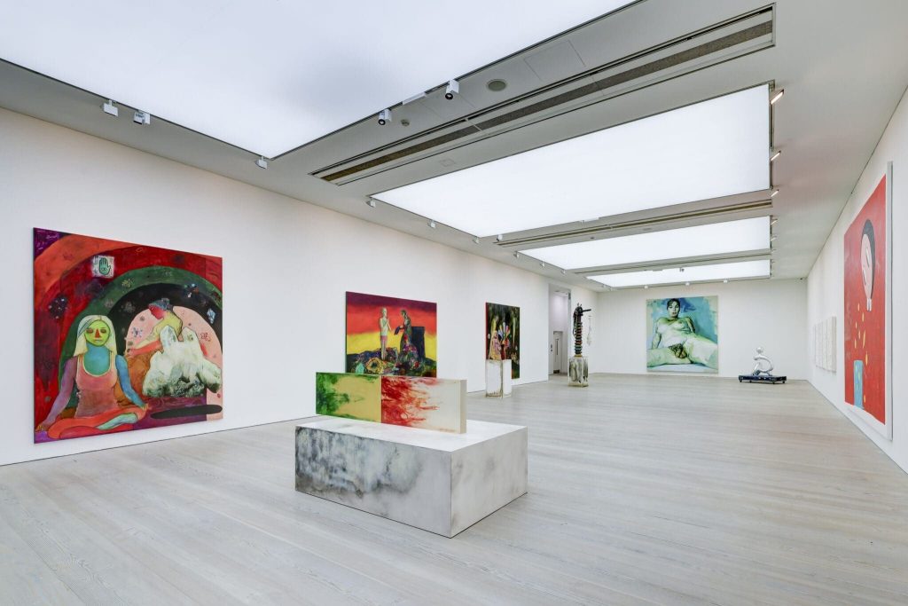Paintings and a marble plinth in a skylit gallery