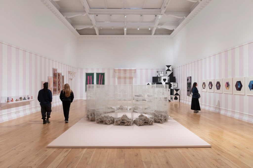 Visitors walking around a low installation and wall works