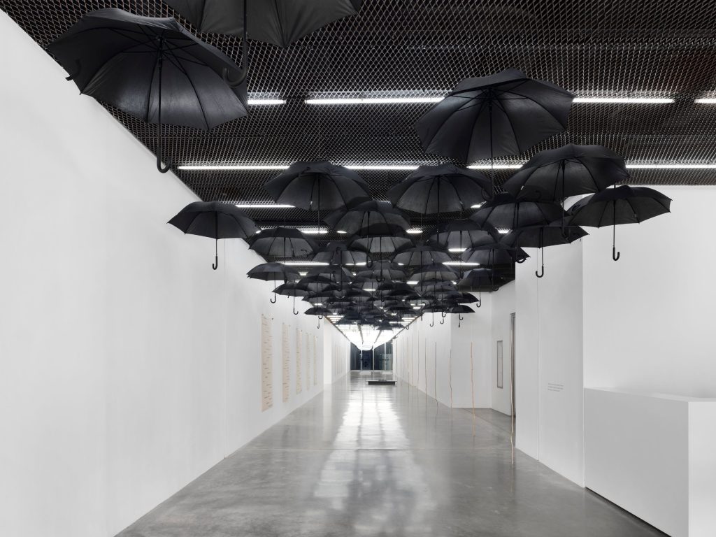 Black umbrellas suspended from a dark ceiling